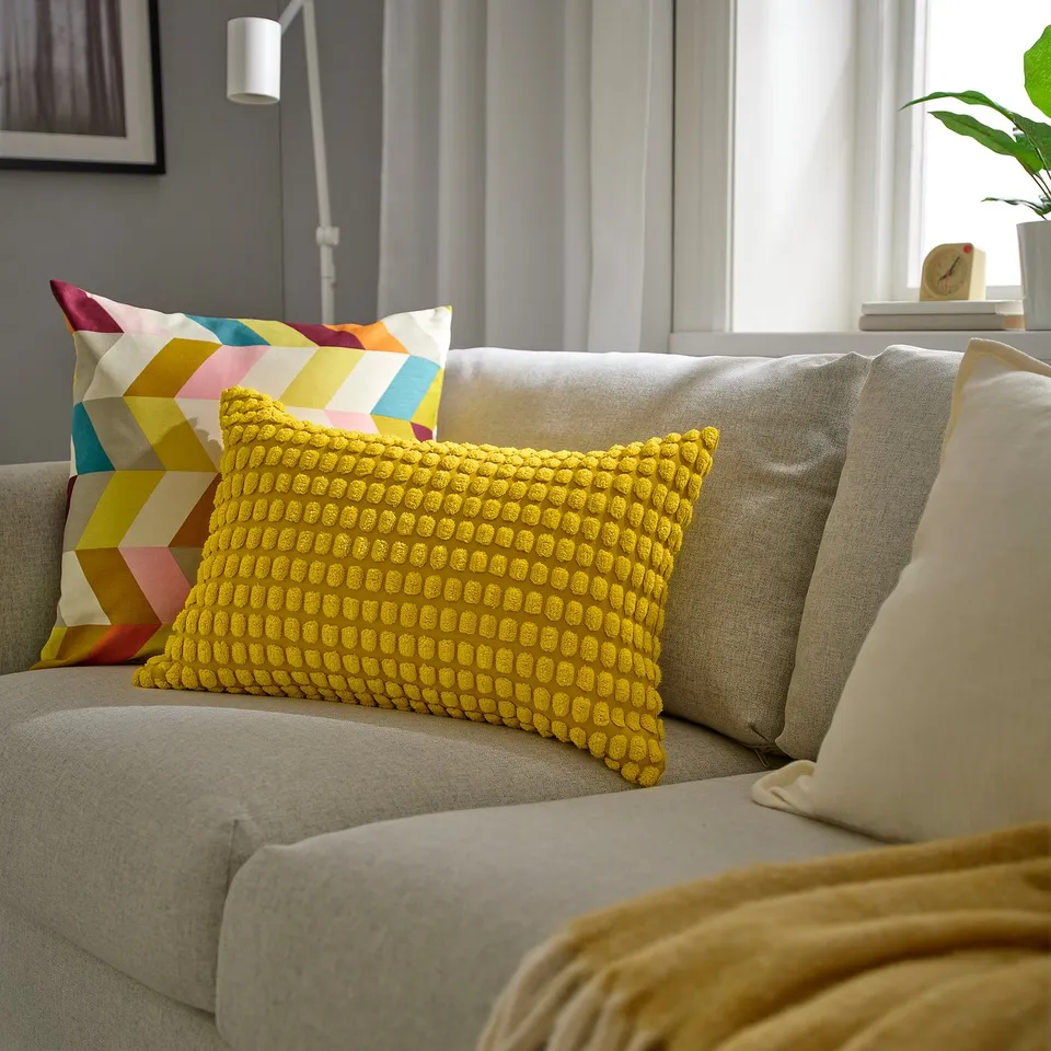 Living room with grey sofa, colourful pillows; large yellow pillow stands out.