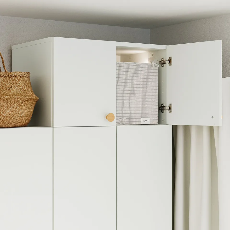 White cabinet with one door open, revealing inside. On top, a wicker basket is placed.