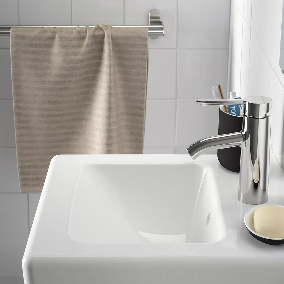 Modern bathroom sink with chrome tap and toothbrush holder.