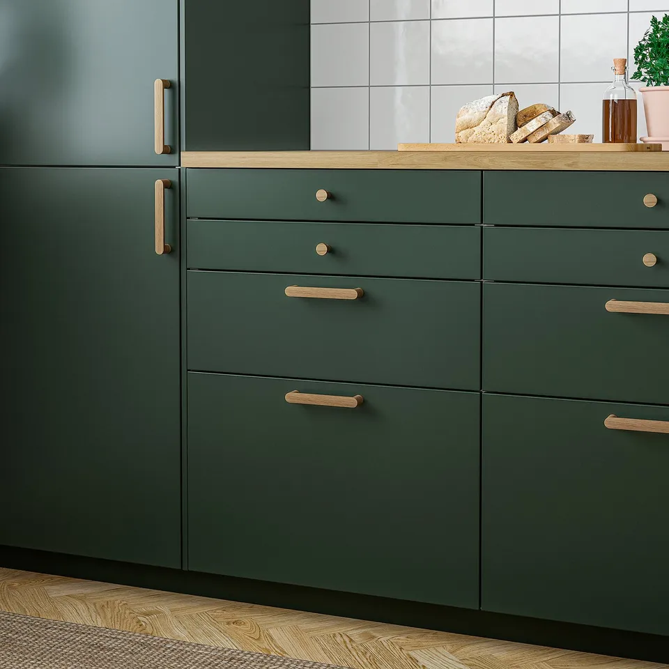Dark green kitchen cabinets with oak handles, sleek and warm wood grain texture.