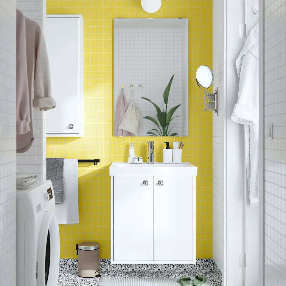 Compact HAVBÄCK vanity in bright yellow-tiled bathroom with modern toiletries, mirror, and washing machine.