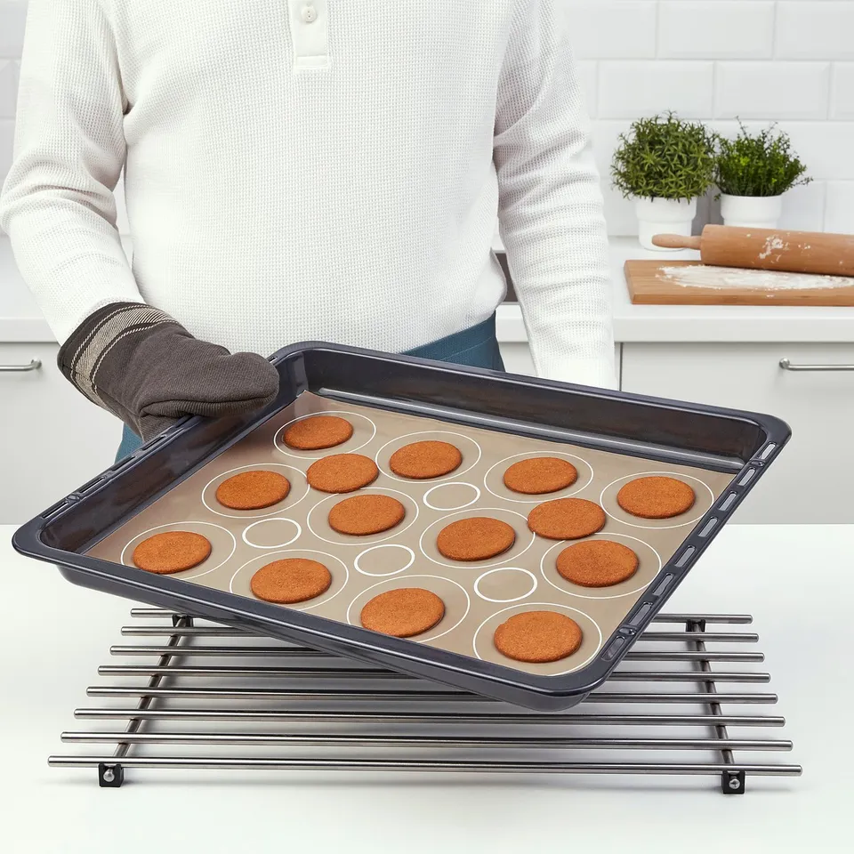 Person holding baking tray with cookies on cooling rack.