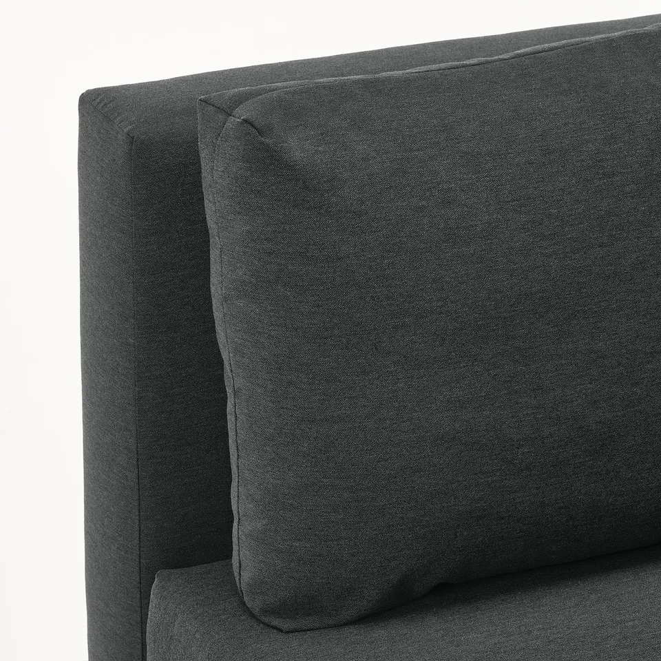 Close-up of stylish, dark grey sofa with curved backrest and plump pillow, showcasing high-quality upholstery and comfortable design.