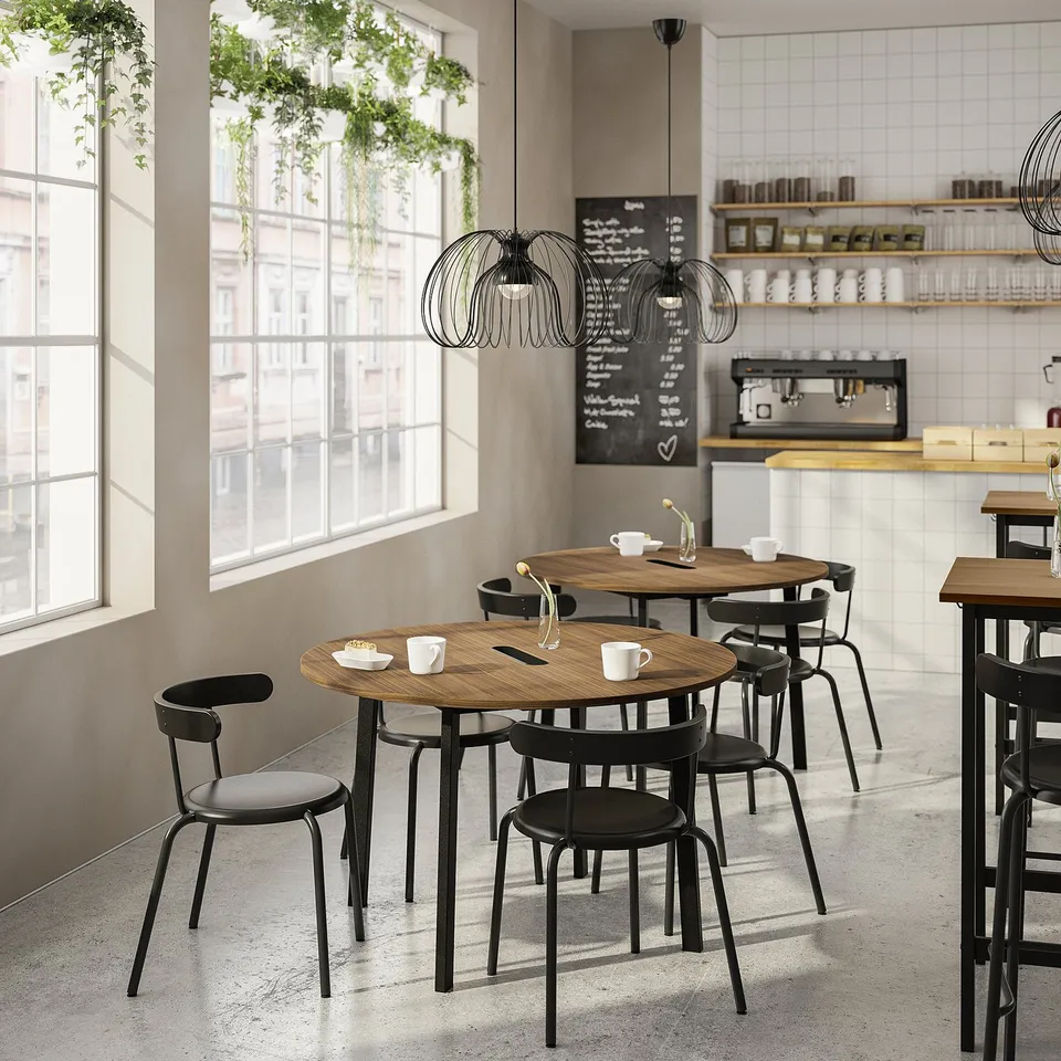 Modern café with wooden tables, black chairs, plants, chalk menu, minimalist design.