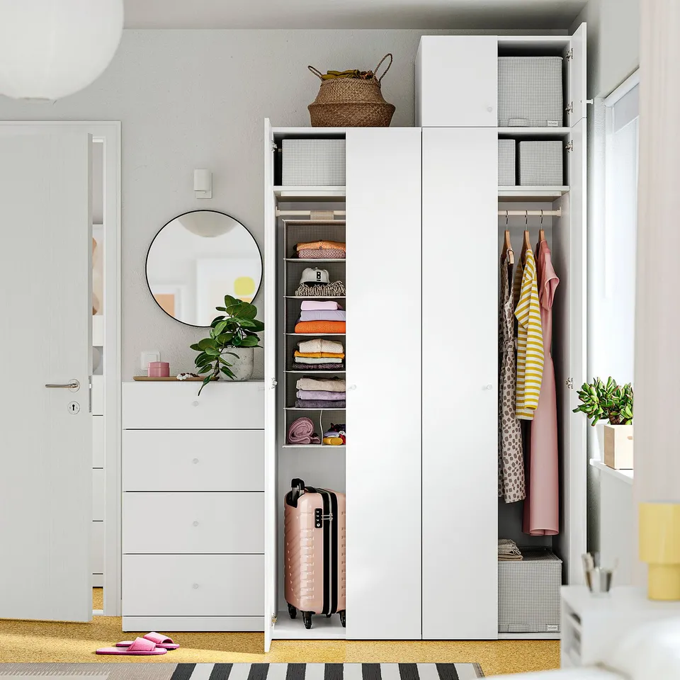 Organised closet with shelves, hanging clothes, and pink suitcase.