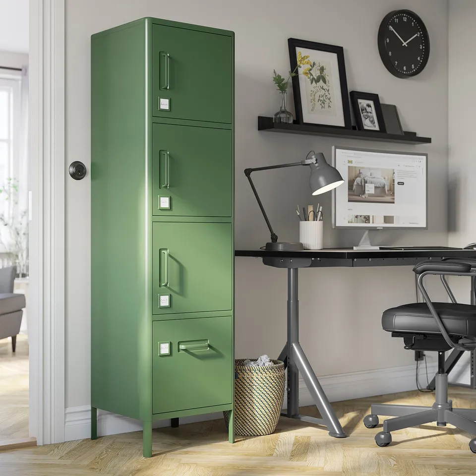 Olive green IDÅSEN locker beside home office desk, tall with multiple compartments and silver accents.