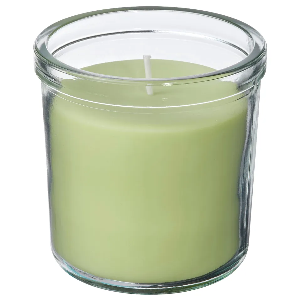 Round green scented candle in clear glass jar.