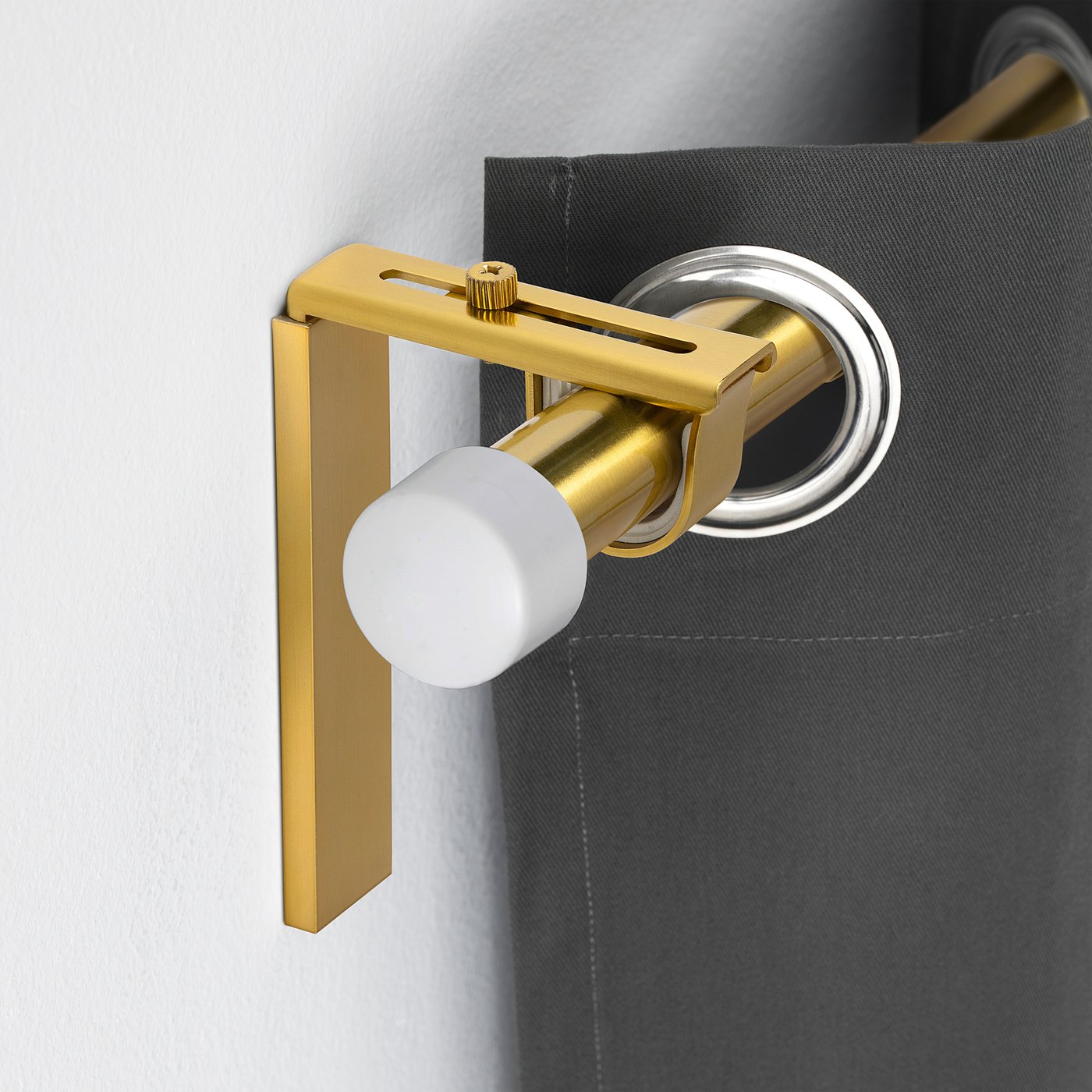 Gold BETYDLIG curtain rod holder against grey wall. Adjustable, modern design. Small in size.