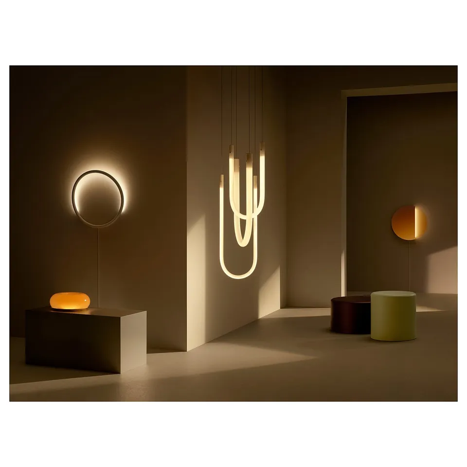 Modern room sleek, circular hanging and table lamps with warm, dim lights. Lamps have minimalist design with orange glass and metal finish.