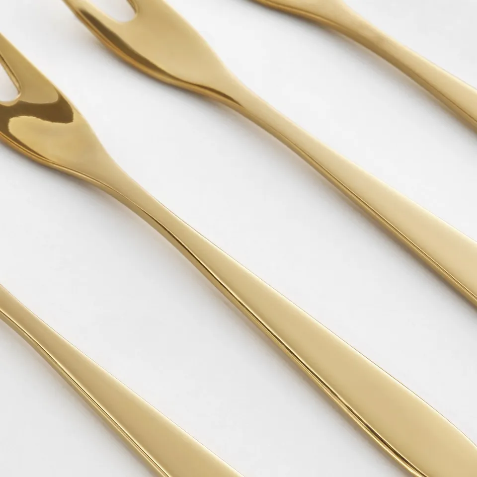 Gold-colored metal forks; sleek, shiny, and elegant; arranged neatly, reflecting light.