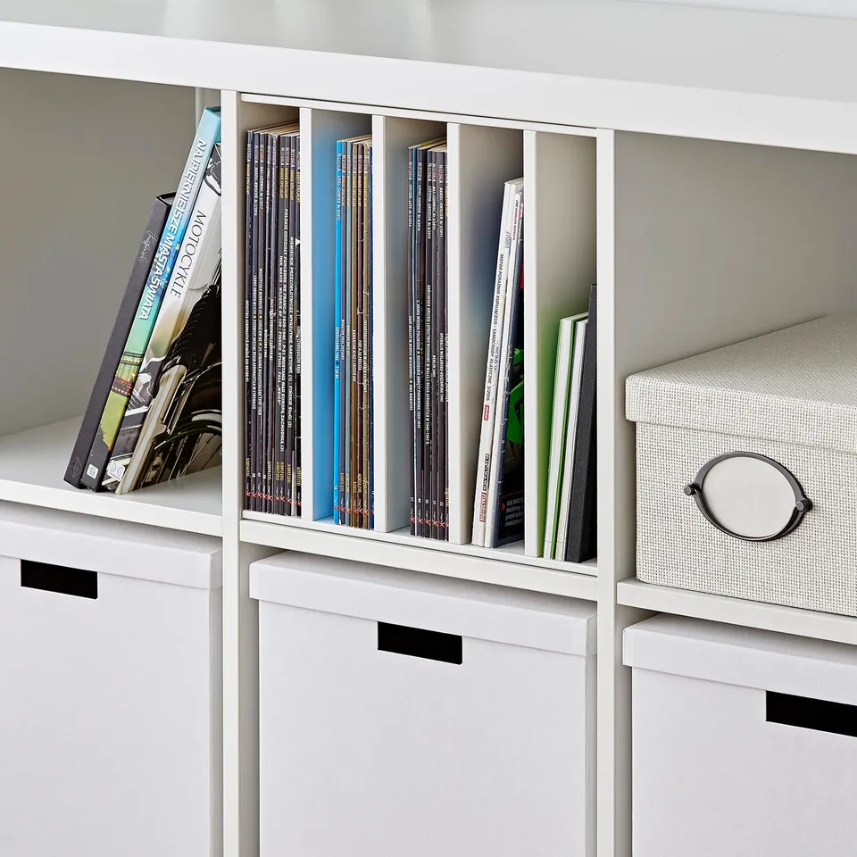 White bookshelf with black handles and dividers; holds books, magazines, and a box.
