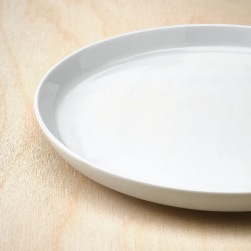 Clean, simple white porcelain plate on a light wooden surface.