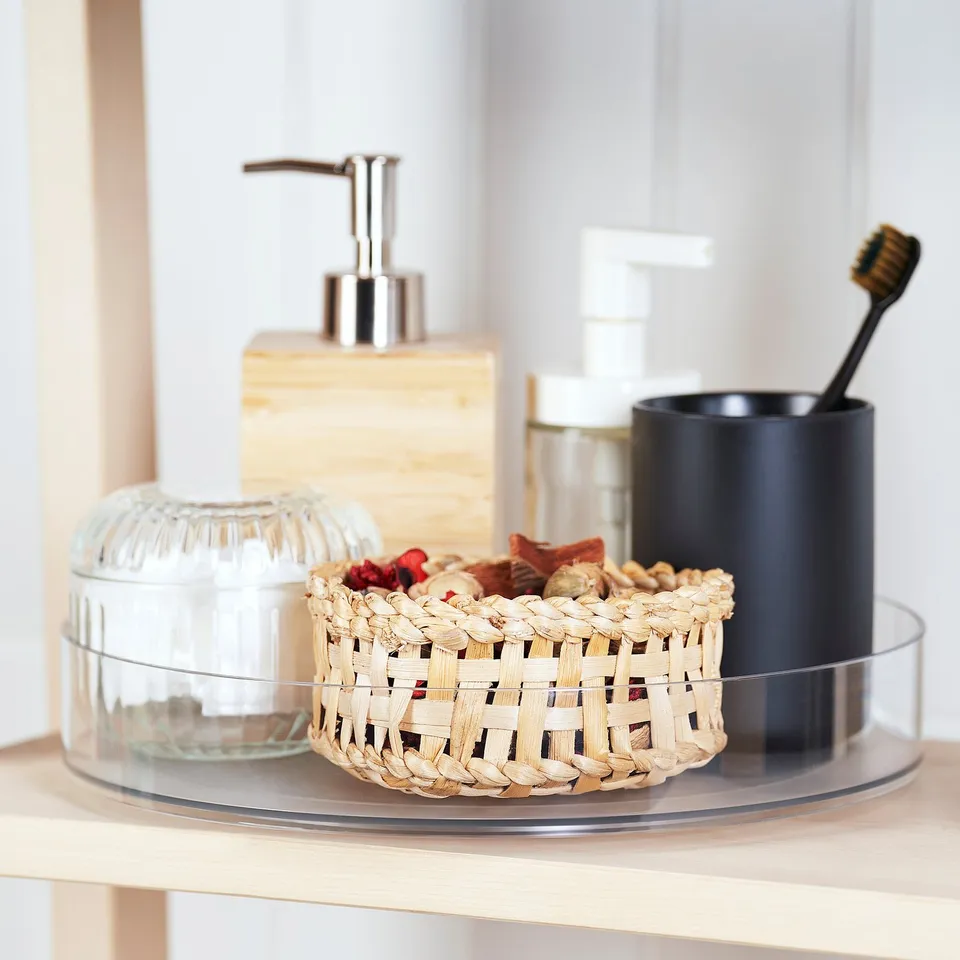 Glass turntable with soap dispenser, toothbrush holder, and basket for bathroom items.
