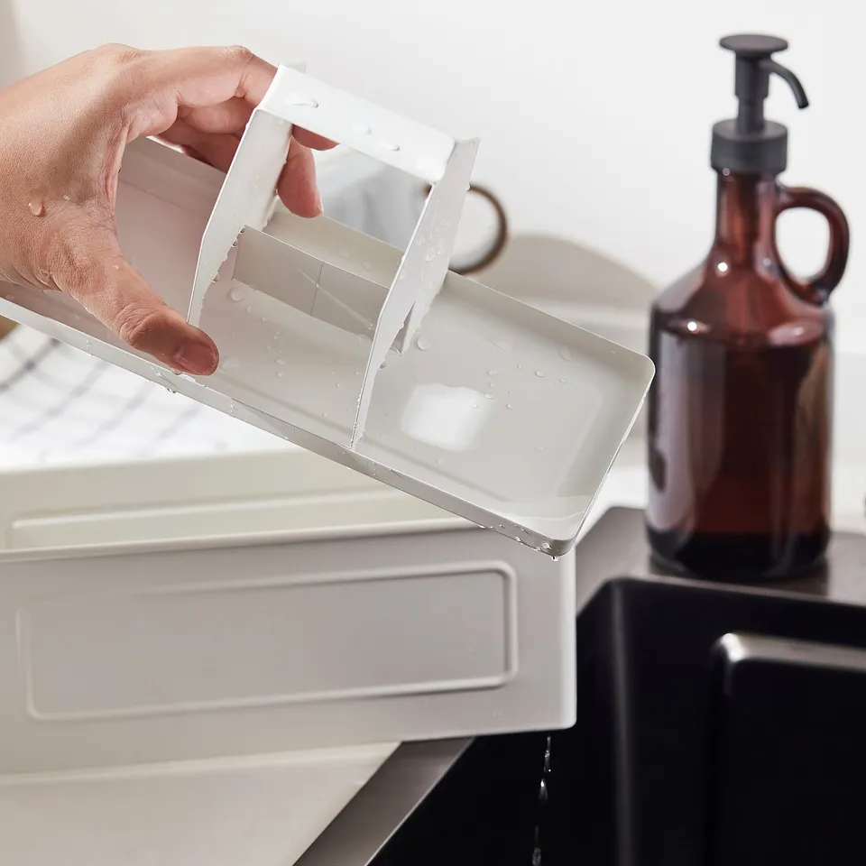 Holding VÄLVÅRDAD kitchen organiser, pouring water; keeps sink area tidy.