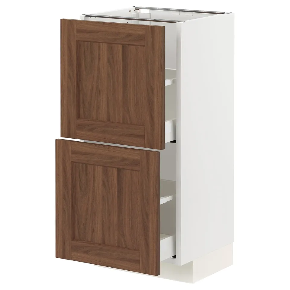 An ikea METOD kitchen cabinet with walnut-patterned fronts. Its white with two wooden drawers and an open shelf.