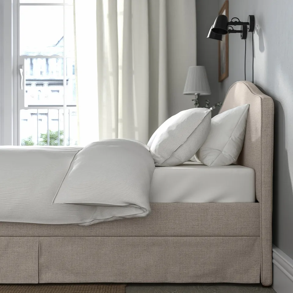 RAMNEFJÄLL bed with beige cover, white linens, wall lamp.