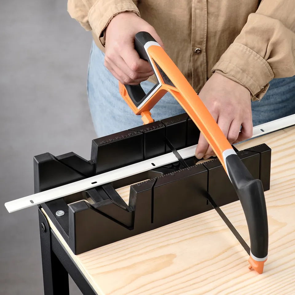 Person cutting white rod with guided tool on wood.