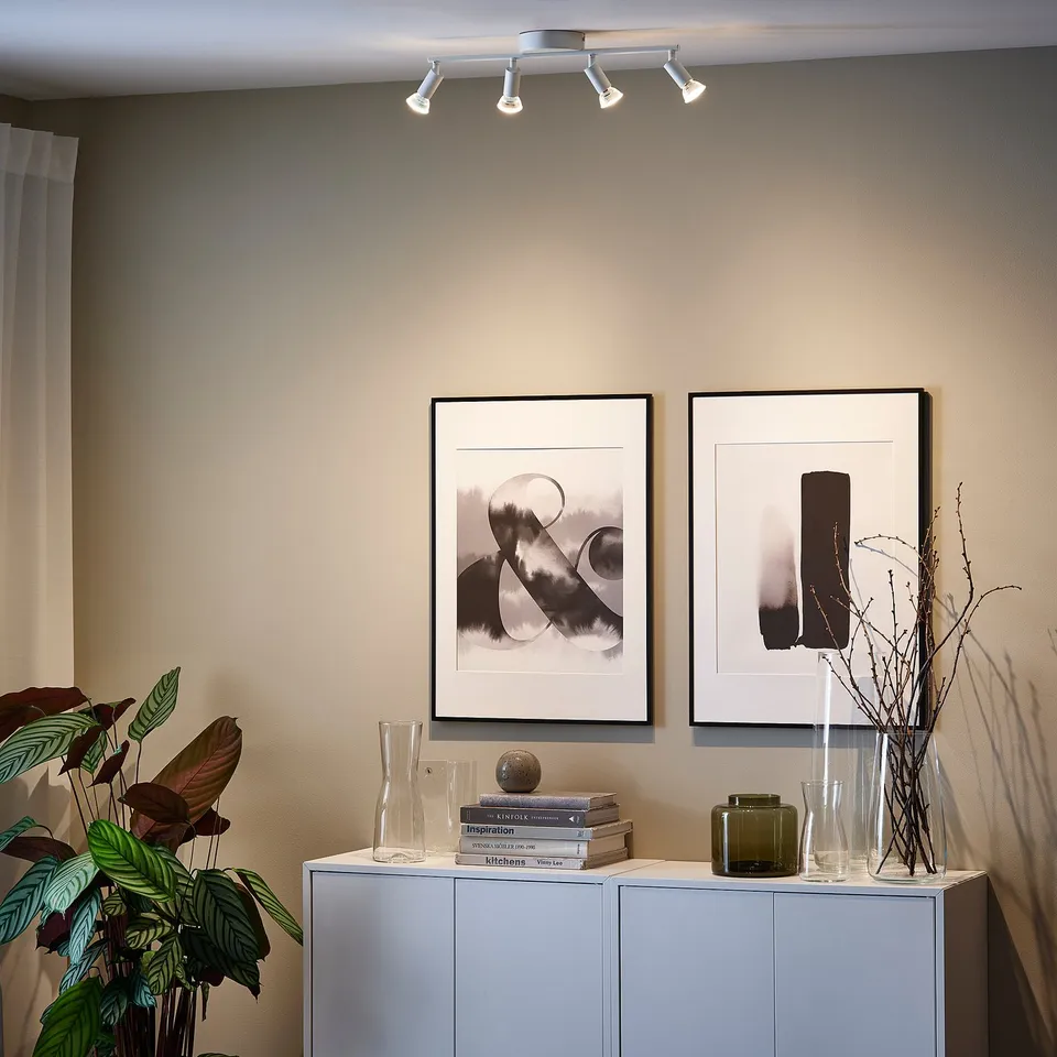 Minimalist living room with ceiling light highlighting art, sideboard with decor.