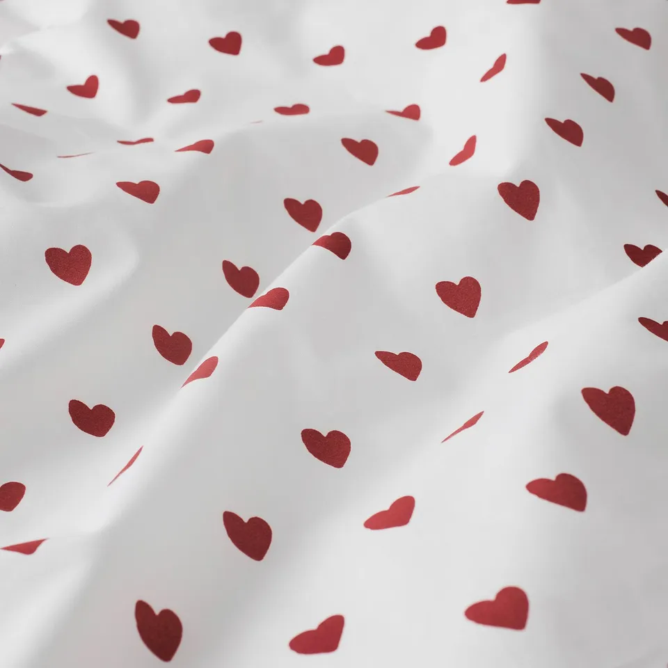 White duvet cover with scattered maroon hearts, showing soft, comfy cotton fabric with neat, even stitching.