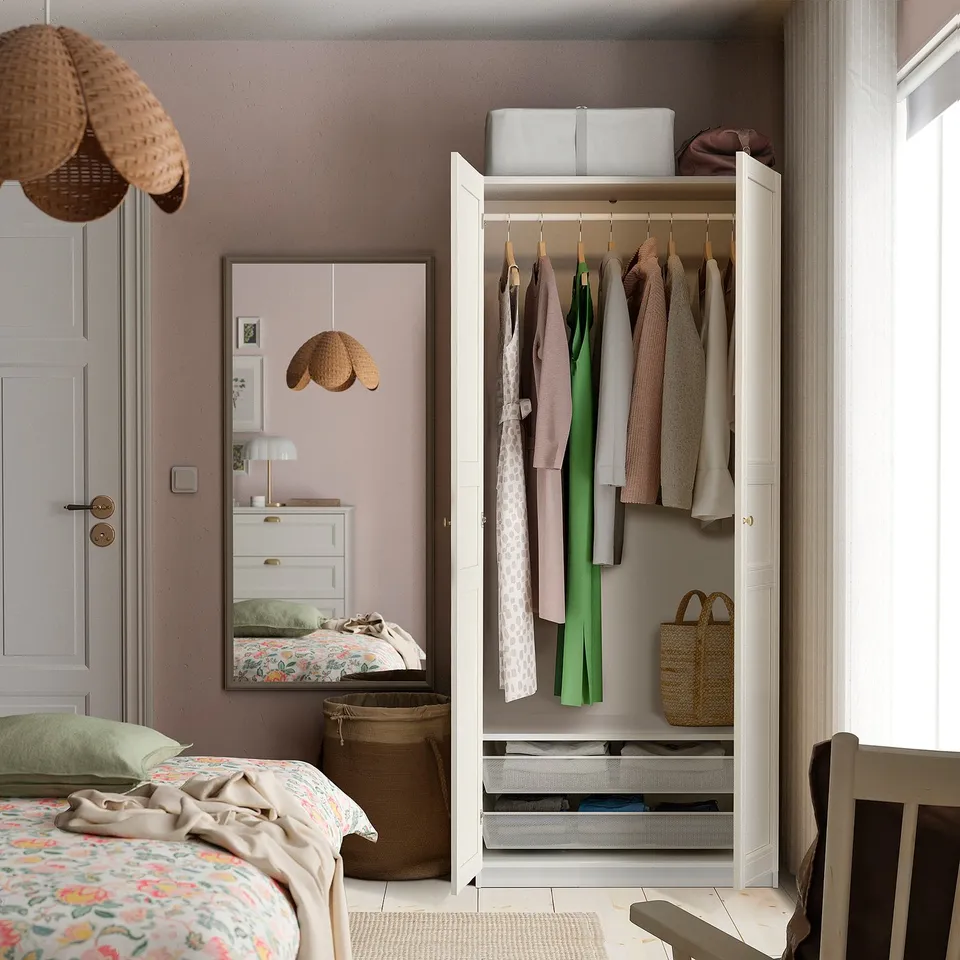 Open closet reveals neatly hung clothes in pastel shades and stacked storage on top.