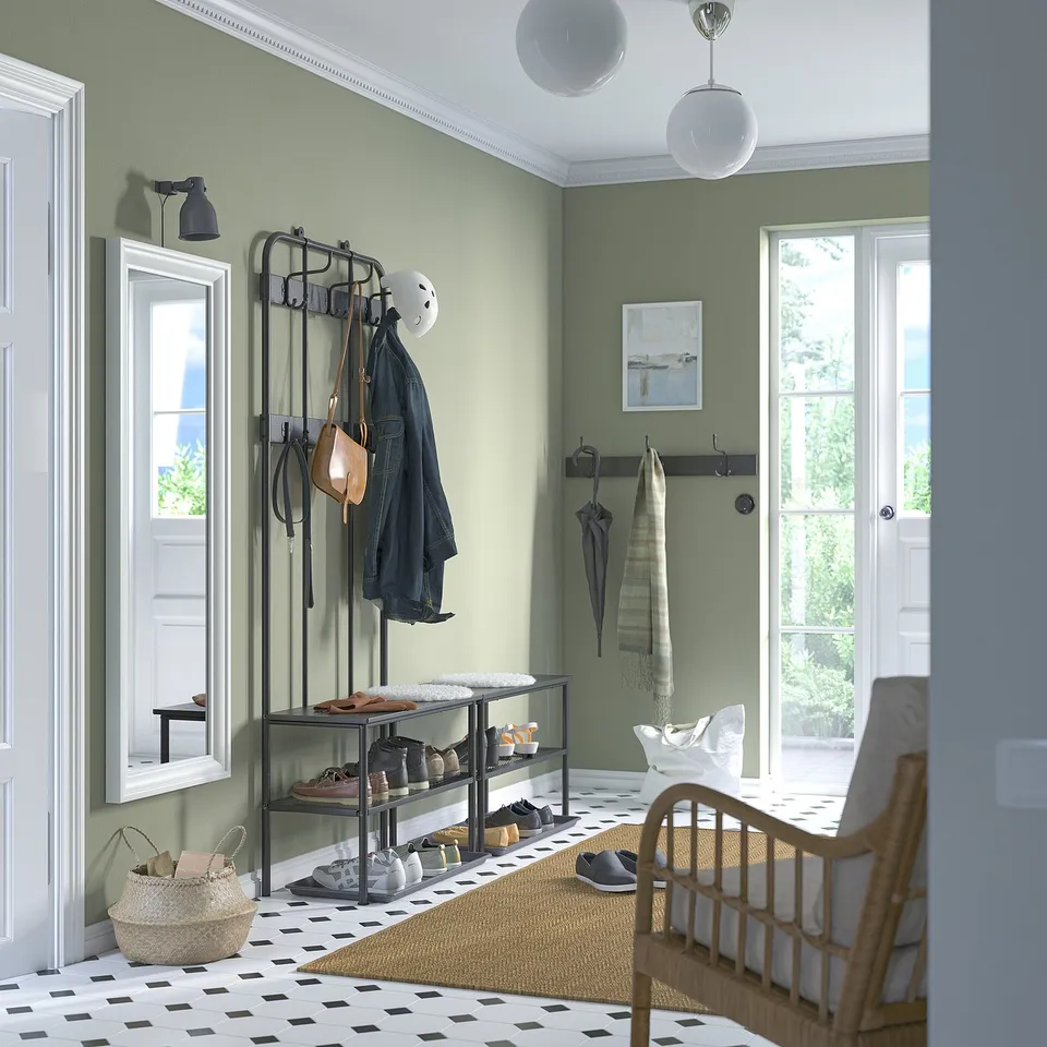 Modern entryway with green wall, coat rack, bench, wicker chair, mirror, hooks, black & white tiles, compact NIPÅSEN shoe bench.