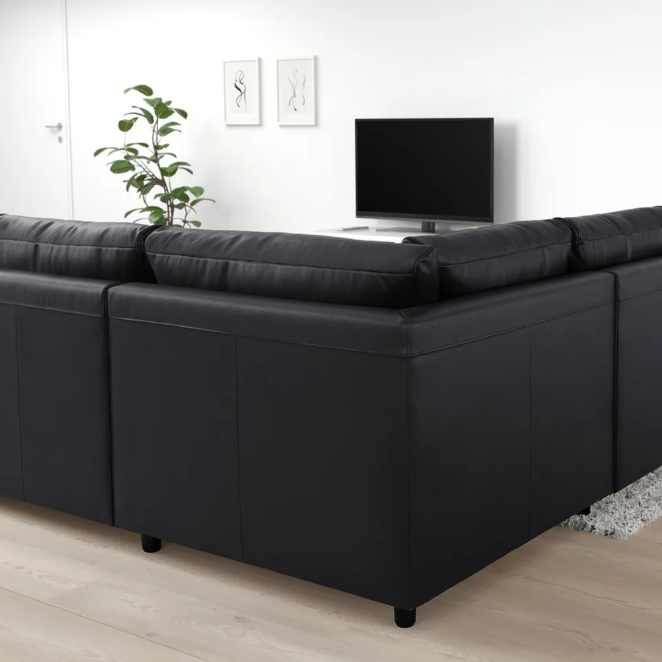 Black VIMLE sectional sofa in modern living room, near tv, with plant.