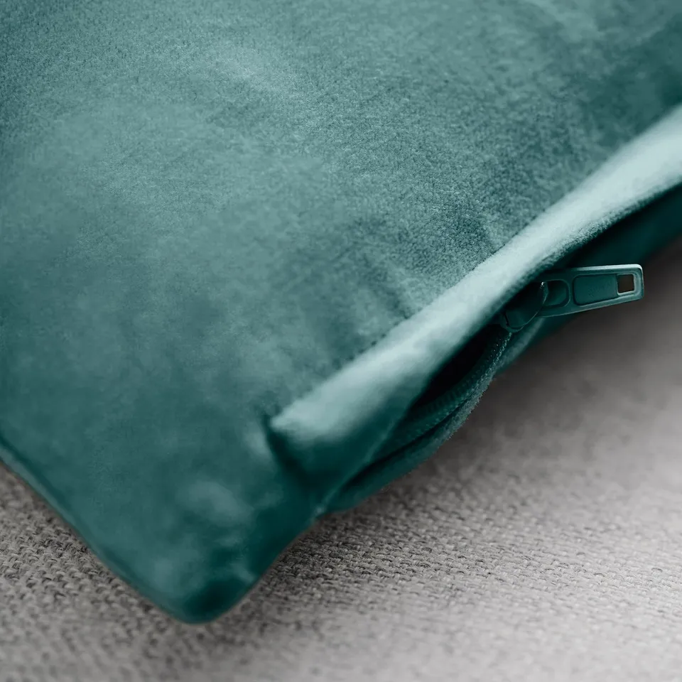 Close-up of plush teal cushion cover with a subtle sheen and a concealed zip, showcasing its smooth texture and high-quality velvet fabric.