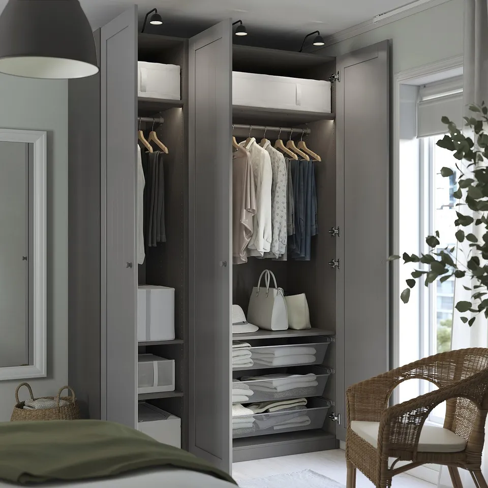Modern closet with PAX system, showing organised clothes on hangers and shelves, baskets, and integrated lighting.