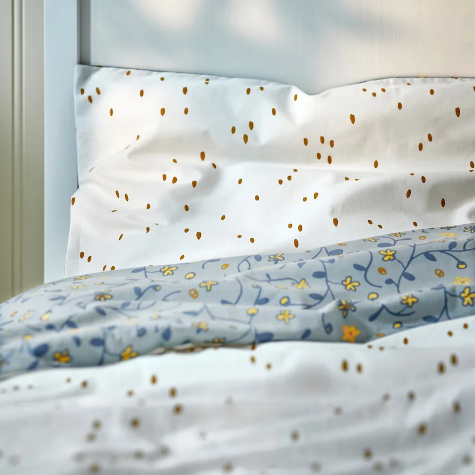 Soft blue bedding with yellow flowers and white dots, made of organic cotton, perfect for babys room.
