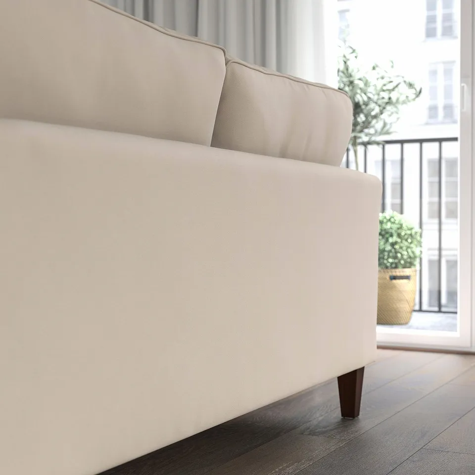 A beige EKHOLMA sofa with pocket spring seat cushions, positioned near a window with plants. Soft, comfy, and durable, its designed for everyday use.