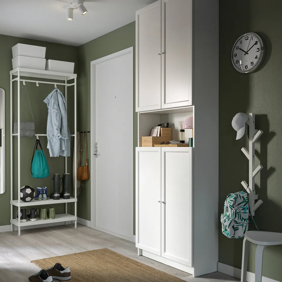 Well-organized room with ikea BILLY bookcase. Tall, narrow, fits between door and coat stand. Blends with green walls and wooden floor.