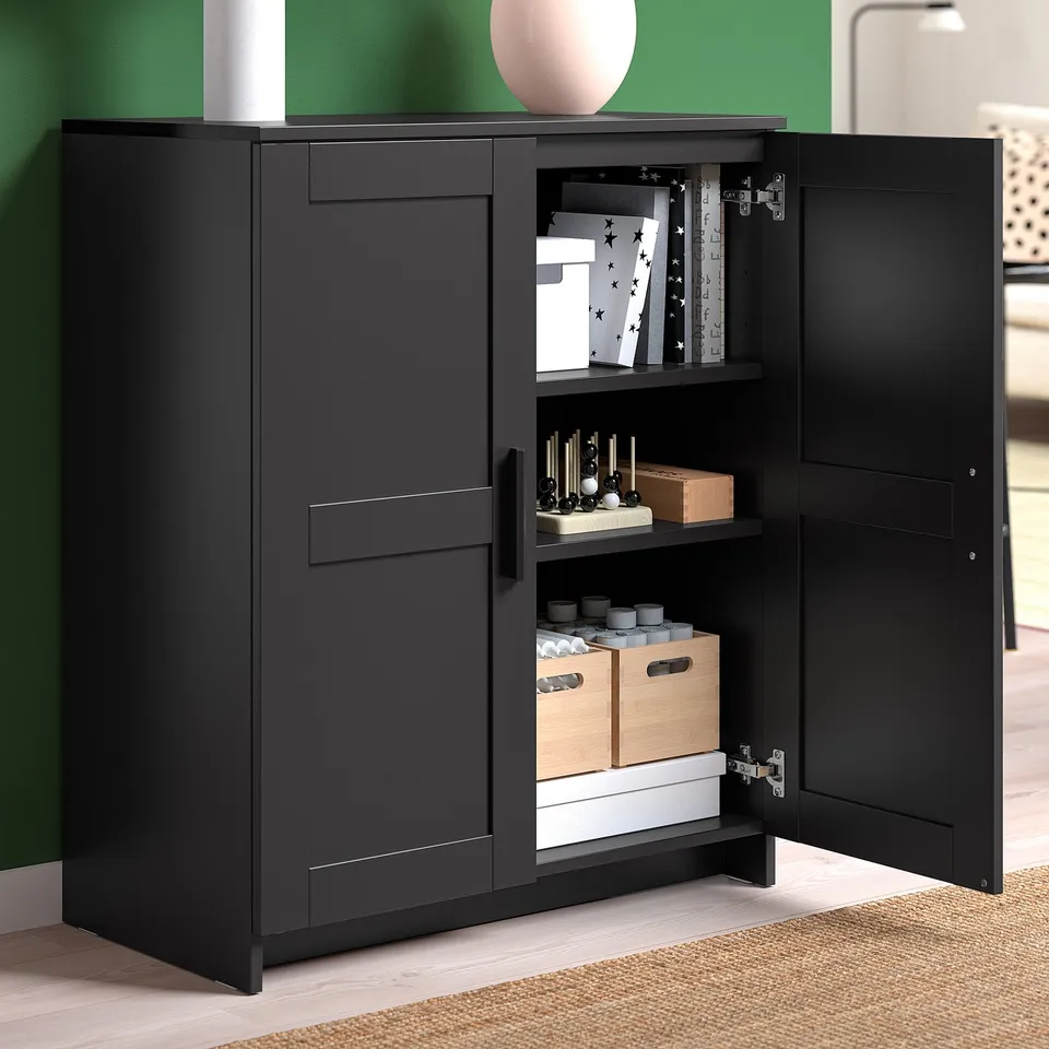 Black tv stand with open doors showing storage for boxes, game controllers, and books. Hidden cable management and adjustable shelves.