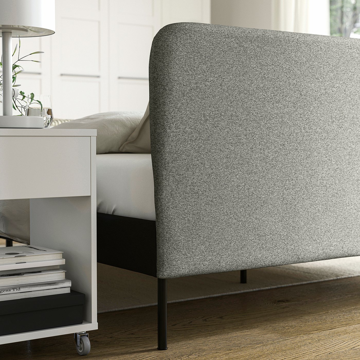 Bed frame with removable slipcover near table.