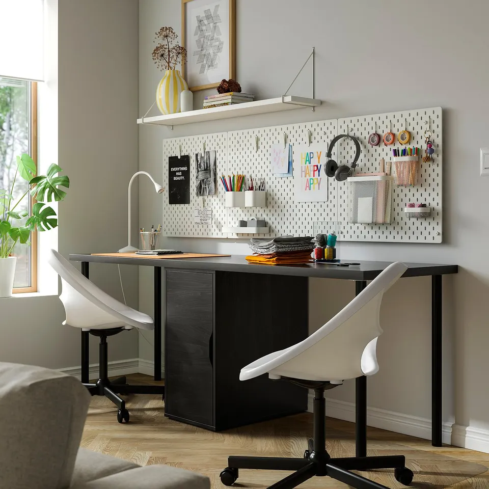 LAGKAPTEN desk in home office, black & white, spacious with storage, two chairs, pegboard, and wall shelf.