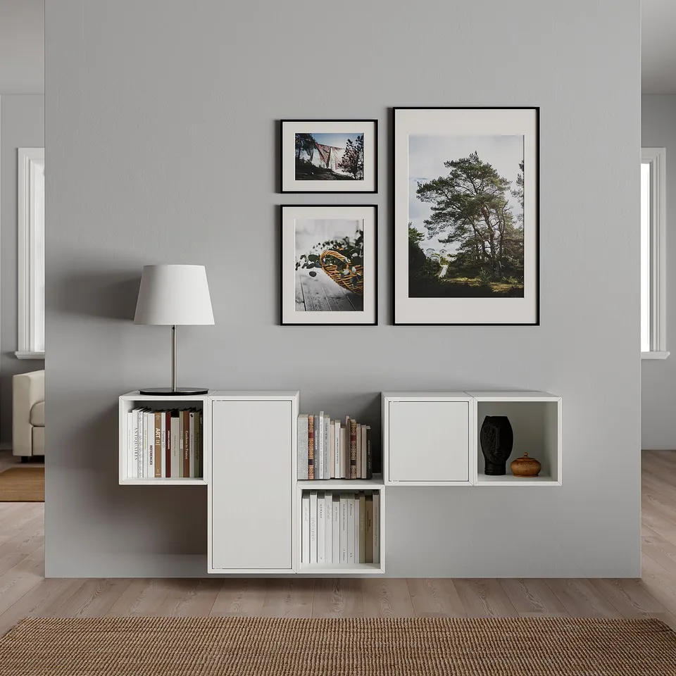Modern minimalist living room a grey wall with mounted white modular shelving and framed nature photographs.