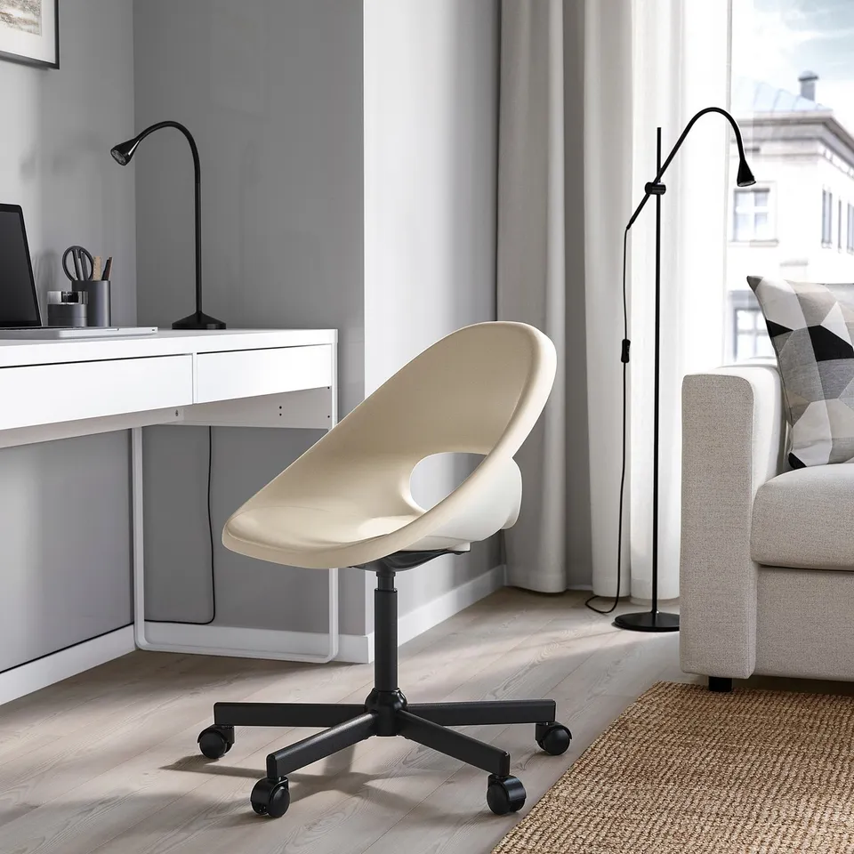 Beige ELDBERGET chair with black wheels, adjusts, fits under desk.