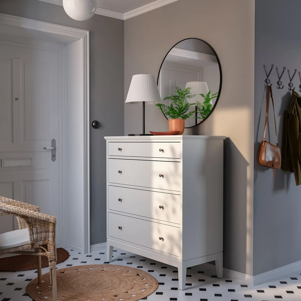 Modern entryway with white IDANÄS chest, round mirror, lamp, and coat hooks.