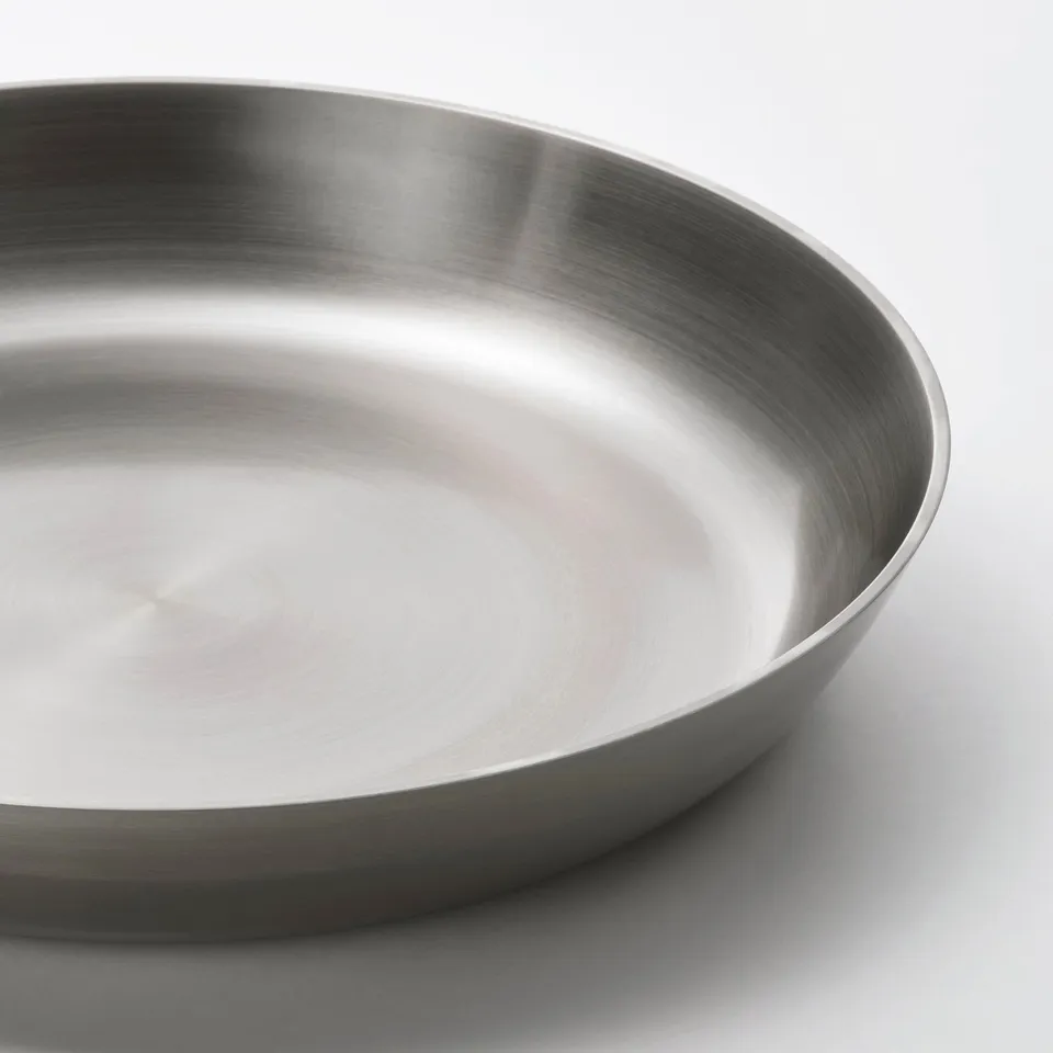 A sleek, stainless steel pan with a smooth, reflective surface and sloped handles, highlighting its high-quality craftsmanship and design.