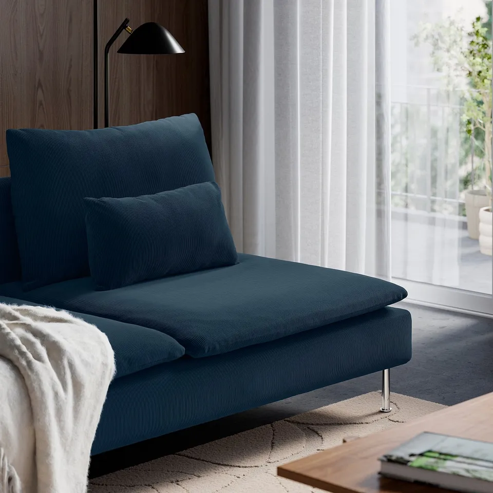 A modern blue sofa, SÖDERHAMN, with deep comfortable seats, loose back cushions, and sleek design, placed near a window with curtains.