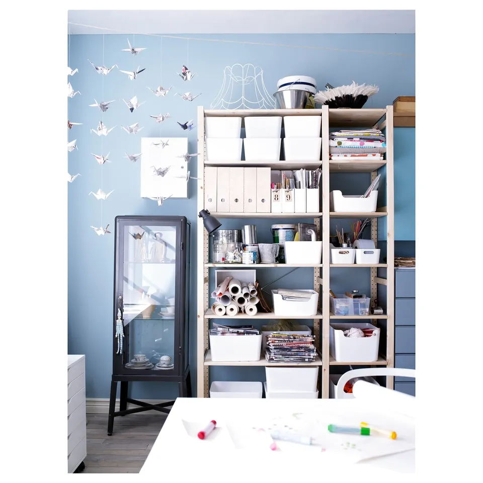 Blue wall IVAR storage with office supplies & art materials, cranes & colourful pens.