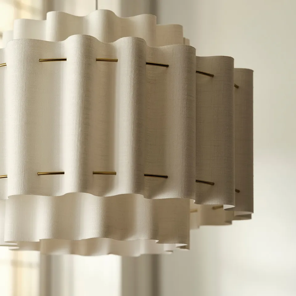 Pendant lamp with wavy, beige textile shade and gold accents, hanging elegantly.