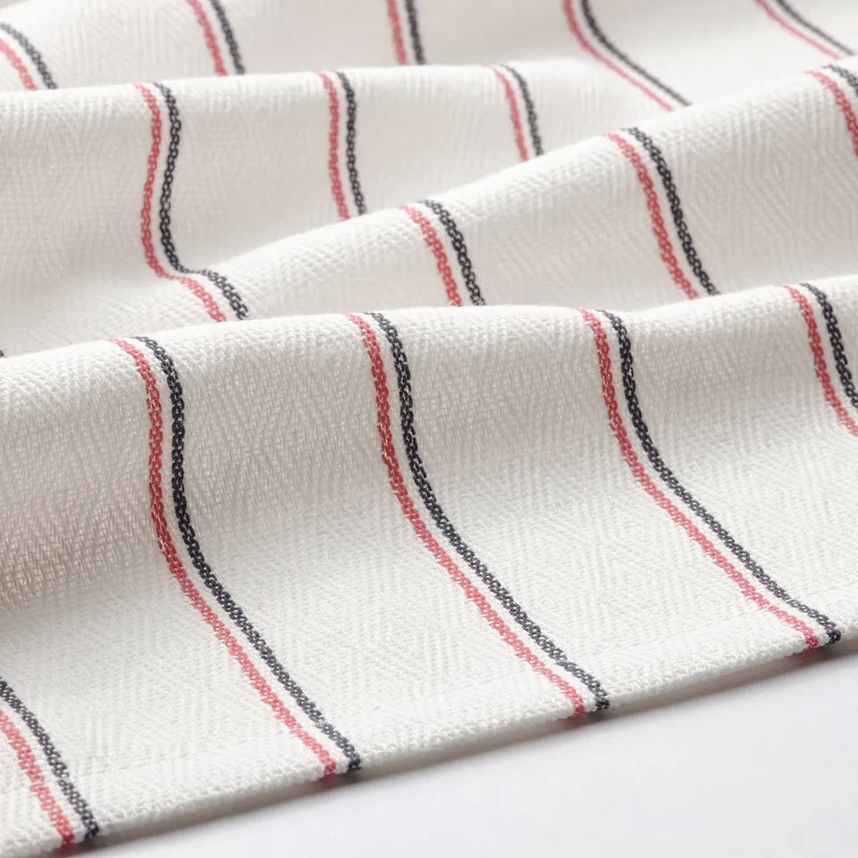 Folded white apron with red and black stripes, showcasing textured cotton material.