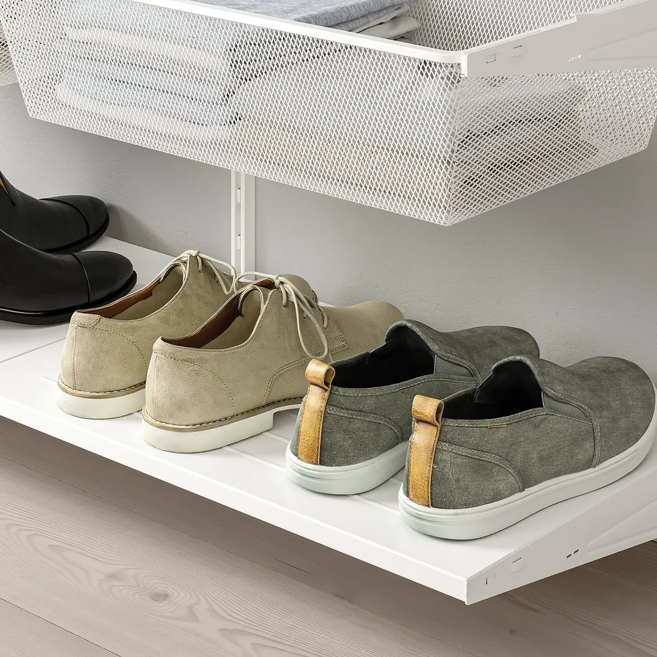 Wall-mounted shoe rack with mesh basket, storing various footwear.