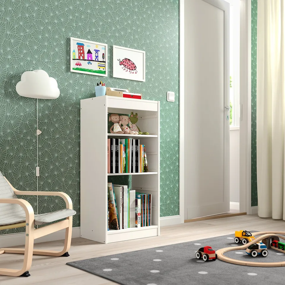 Kids playroom with TROFAST storage, books, toys, poang chair, green wallpaper, art, grey rug, wooden toys.