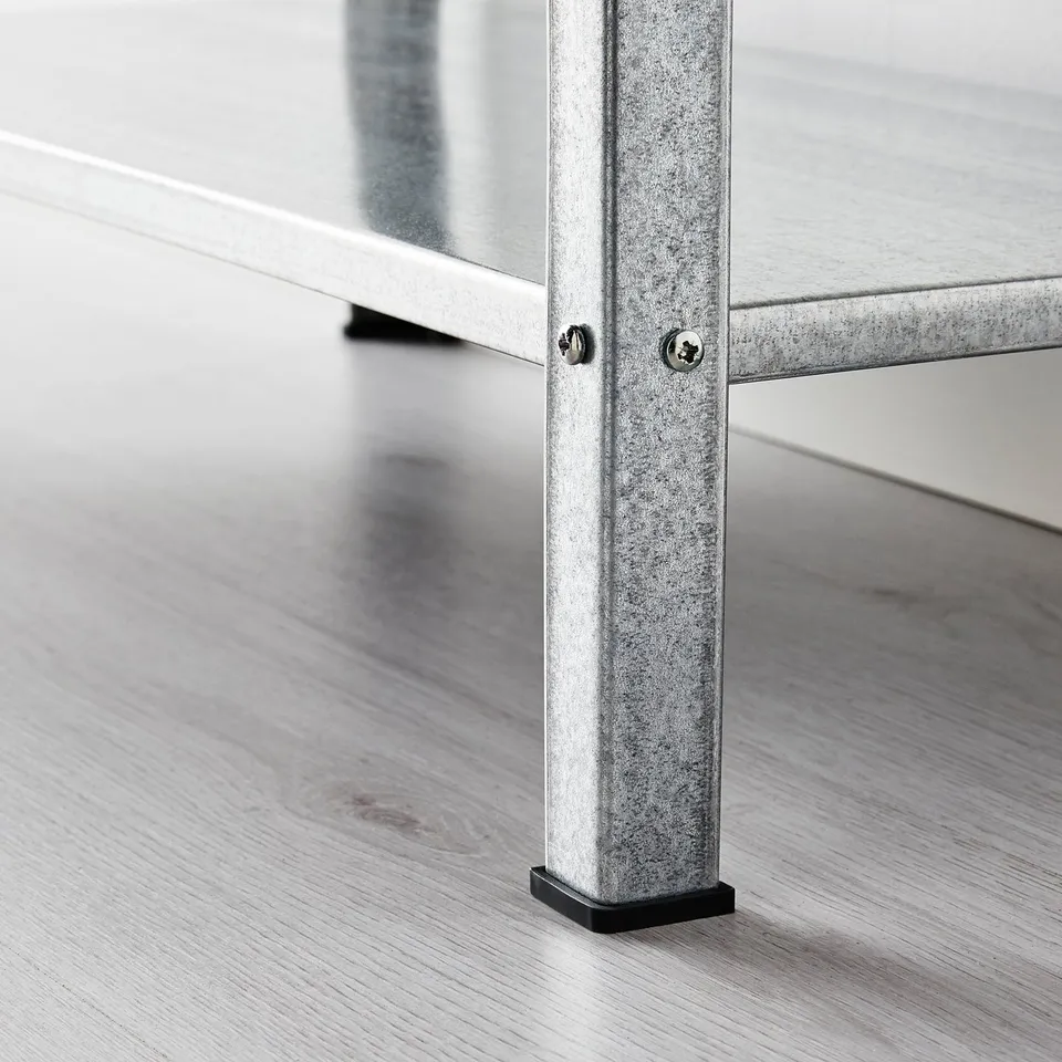 Close-up of a galvanised steel table leg with plastic foot on a wooden floor. Focus on products sturdy and stable design.