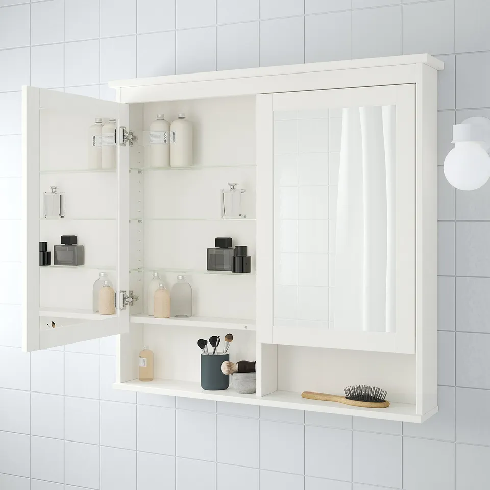 Modern bathroom mirror cabinet open, displaying toiletries on adjustable shelves.