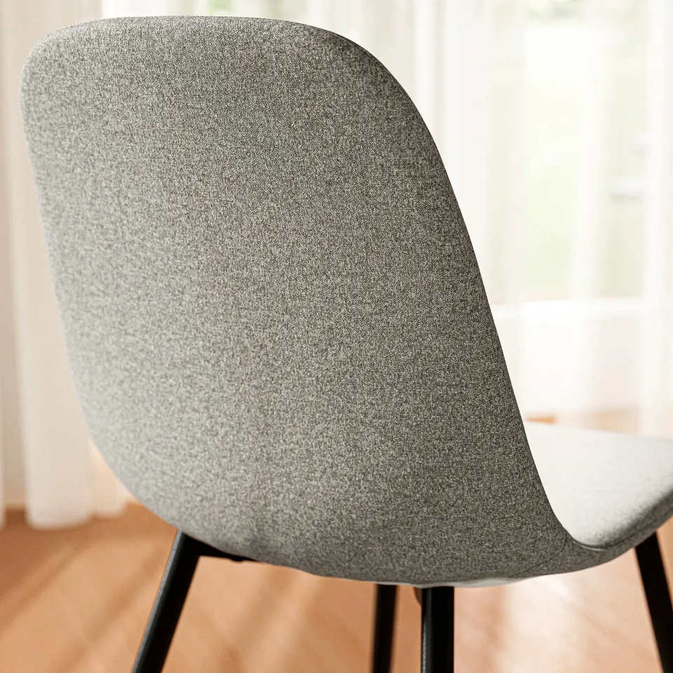 Modern upholstered chair in grey fabric with sleek black legs, designed for comfort and style.