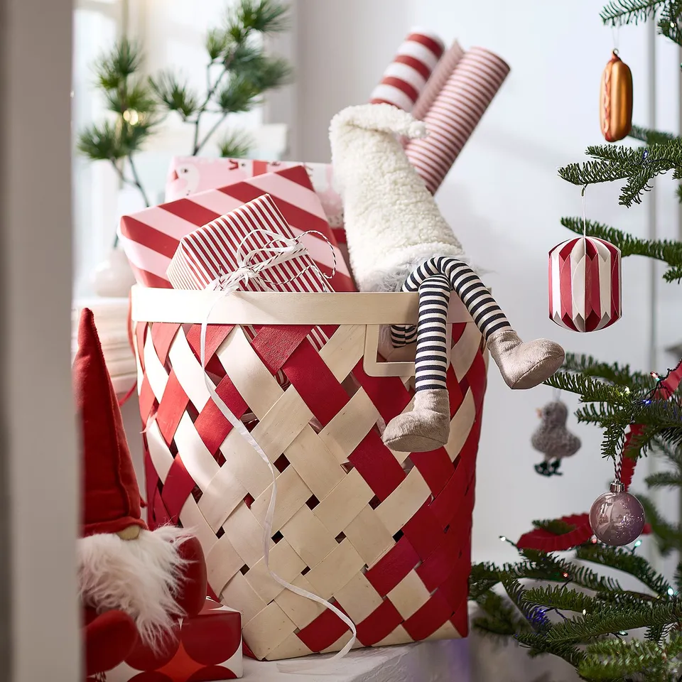 Basket filled with wrapped gifts and cosy items, perfect for holiday decoration or gifting. Santa figure helps spread seasonal cheer.