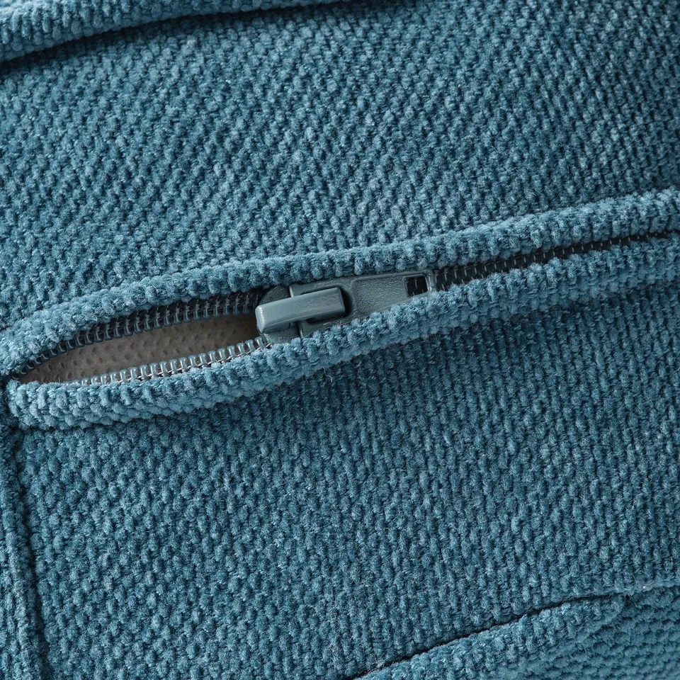 Close-up of a zip on a textured, blue fabric sofa.