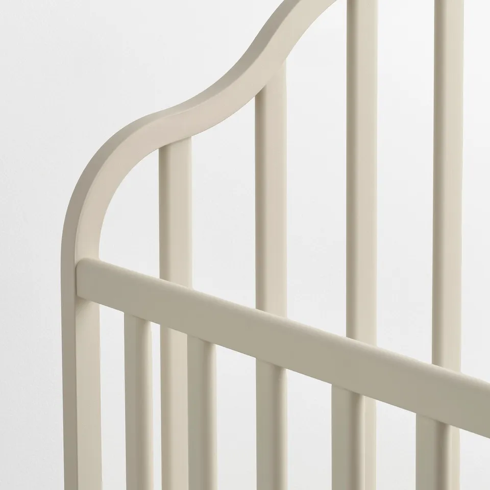 Image shows sturdy, beige metal cot with smooth, rounded edges and evenly spaced bars, designed for safety and comfort.